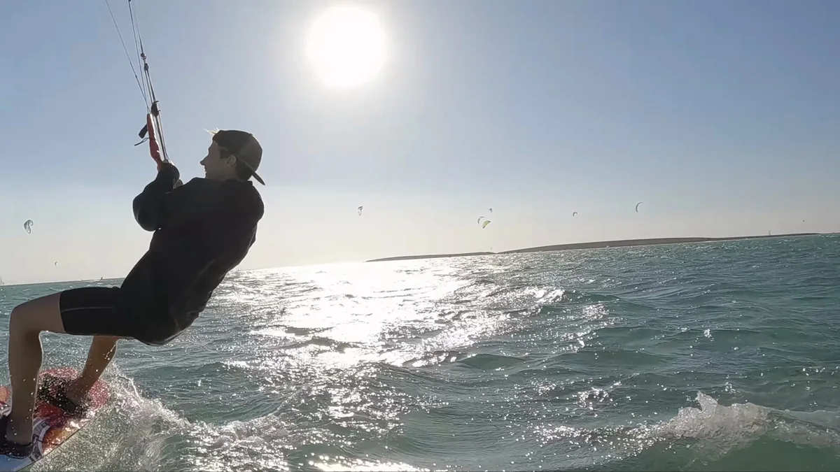 Kiter v protisvětle těsně u kamery, za ním slunce a další kity na obloze