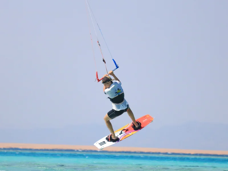 Kiter ve skoku nad tyrkysovou lagunou u písečného ostrova